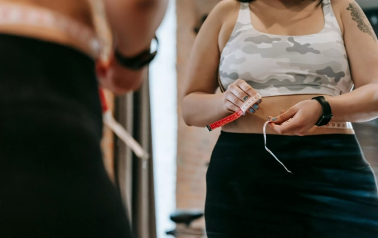 Una chica midiéndose el contorno abdominal/ PEXELS