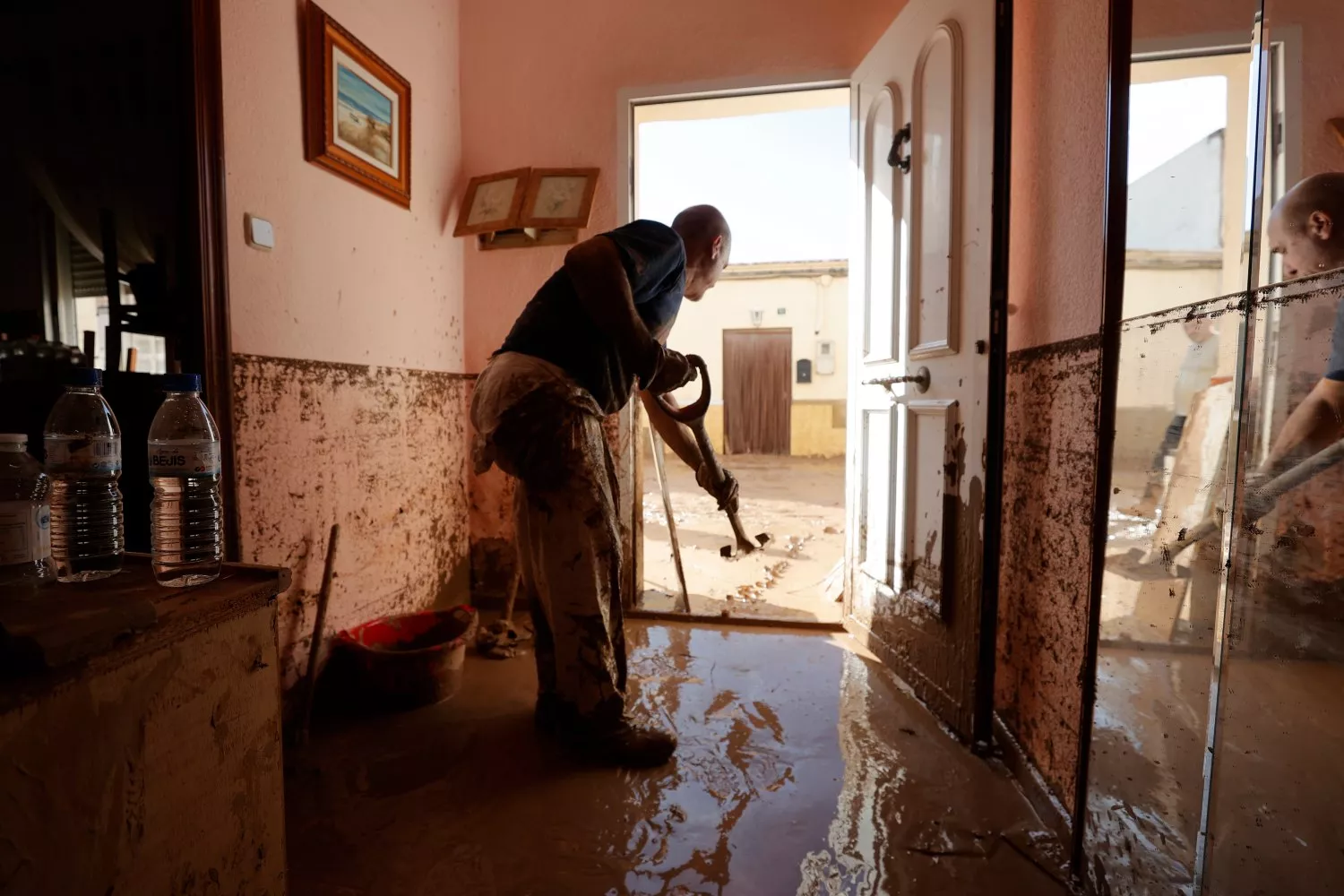 Un hombre retira el lodo acumulado en el interior de su vivienda tras el paso de la DANA / Manuel Bruque - EFE