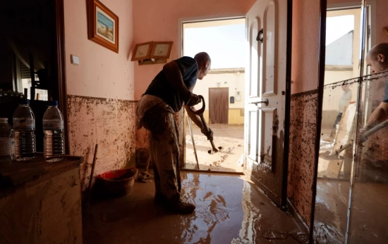 Un hombre retira el lodo acumulado en el interior de su vivienda tras el paso de la DANA / Manuel Bruque - EFE