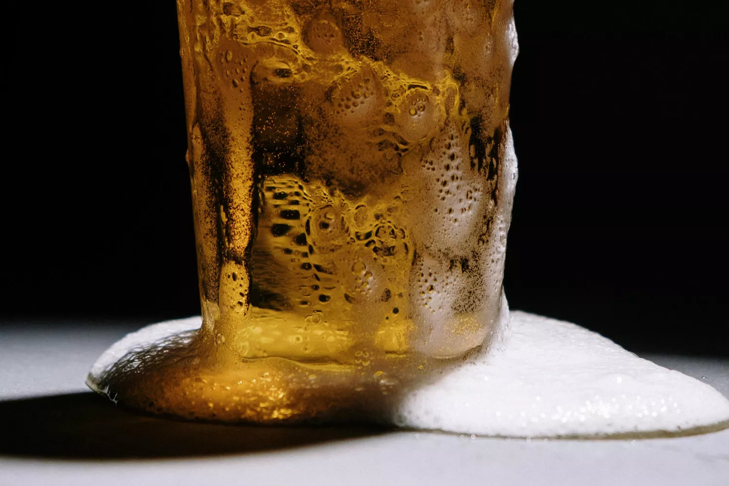 La espuma de la cerveza chorrea en una mesa sin posavasos / PEXELS