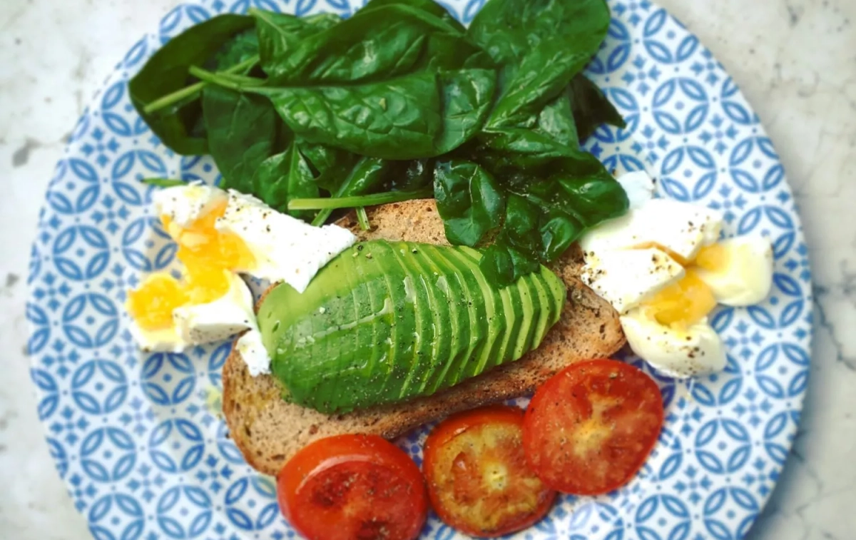 Una tosta de aguacate junto a unas espinacas / FREEPIK