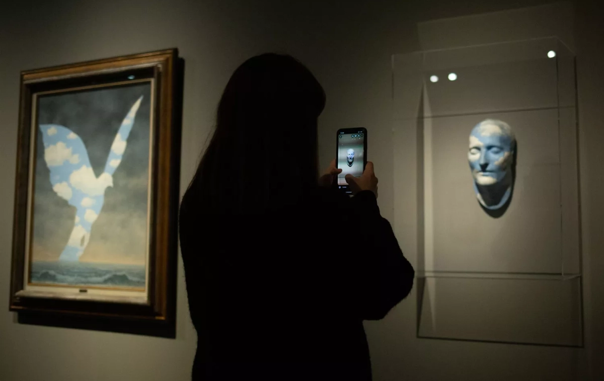 Una persona fotografía una obra de René Magritte en el CaixaForum de Barcelona / DAVID ZORRAKINO - EP