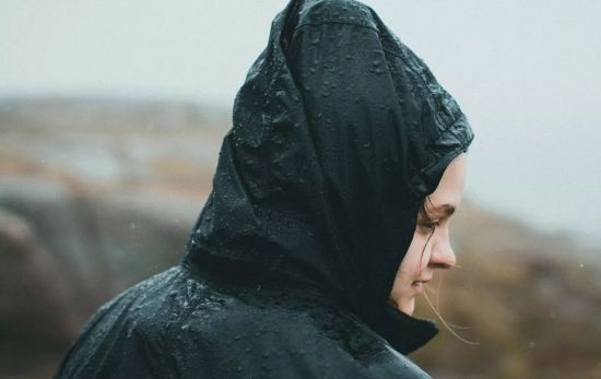 Una mujer se protege de la lluvia con un chubasquero / PEXELS