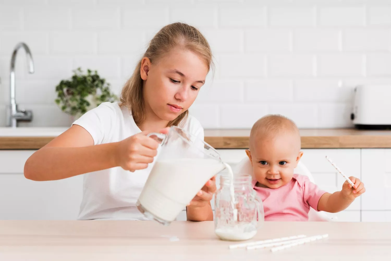 Una niña sirve a un bebé una leche similar a la de Puleva / FREEPIK