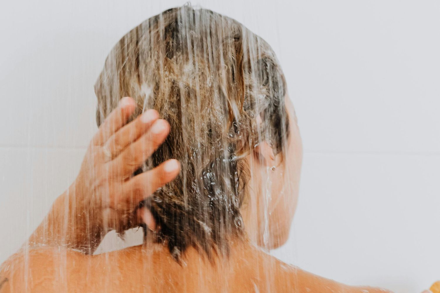 Una mujer lavándose el pelo en la ducha/ PEXELS