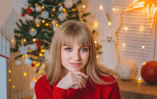 Una mujer en su salón con las luces decorando árbol y paredes de Navidad / PEXELS