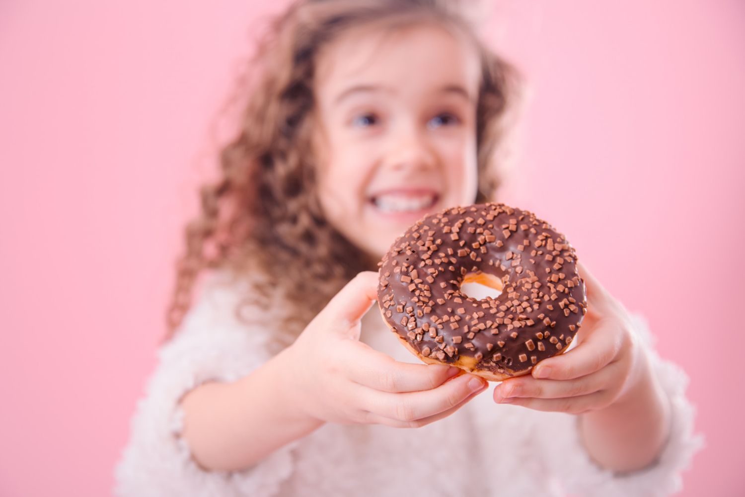 Una niña con un donut, un alimento ultraprocesado / FREEPIK