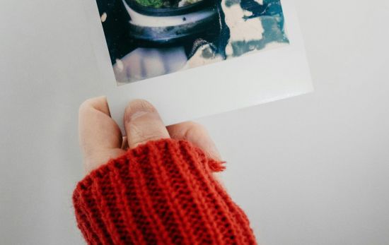 Una persona sujetando una fotografía polaroid/ PEXELS