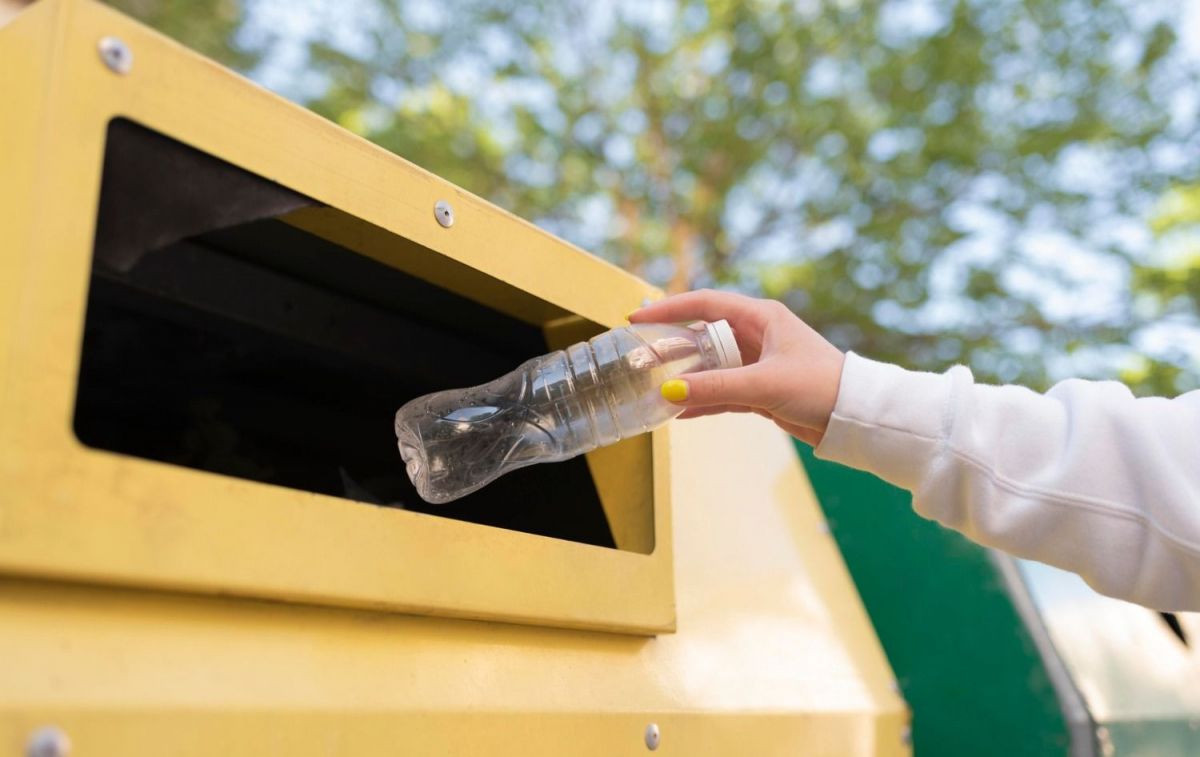 Un consumidor tira una botella a un contenedor / FREEPIK