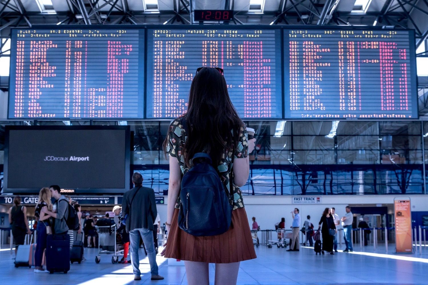 Una chica delante de las pantallas dónde se señala el número de vuelo y el destino 