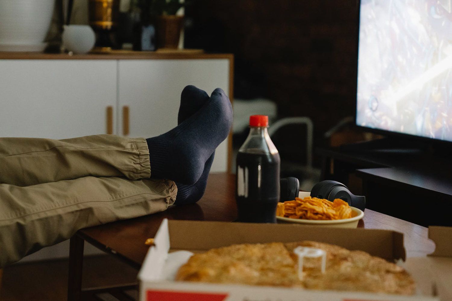 Un hombre junto a alimentos ultraprocesados, como la pizza, los snacks y las bebidas azucaradas / PEXELS