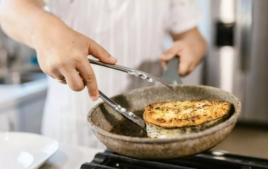 Una persona dorando el salmón en una sartén bien caliente/ PEXELS Una persona dorando el salmón en una sartén bien caliente/ PEXELS