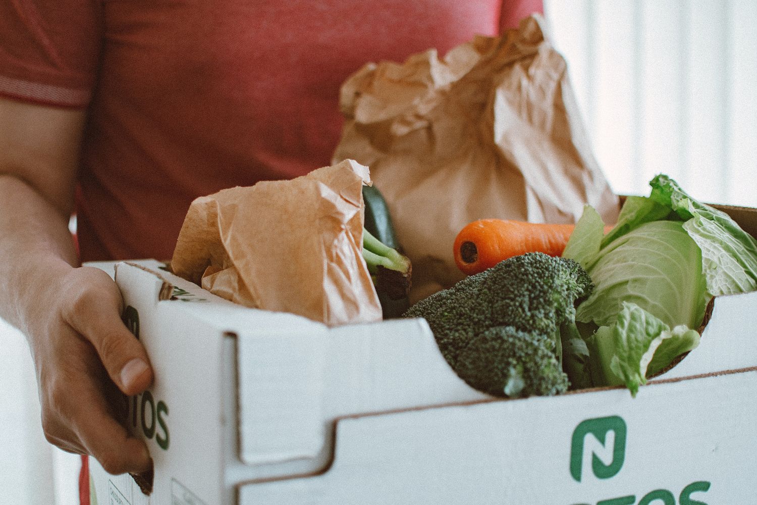 Una persona carga con una cesta de frutas y verduras de temporada / Pexels