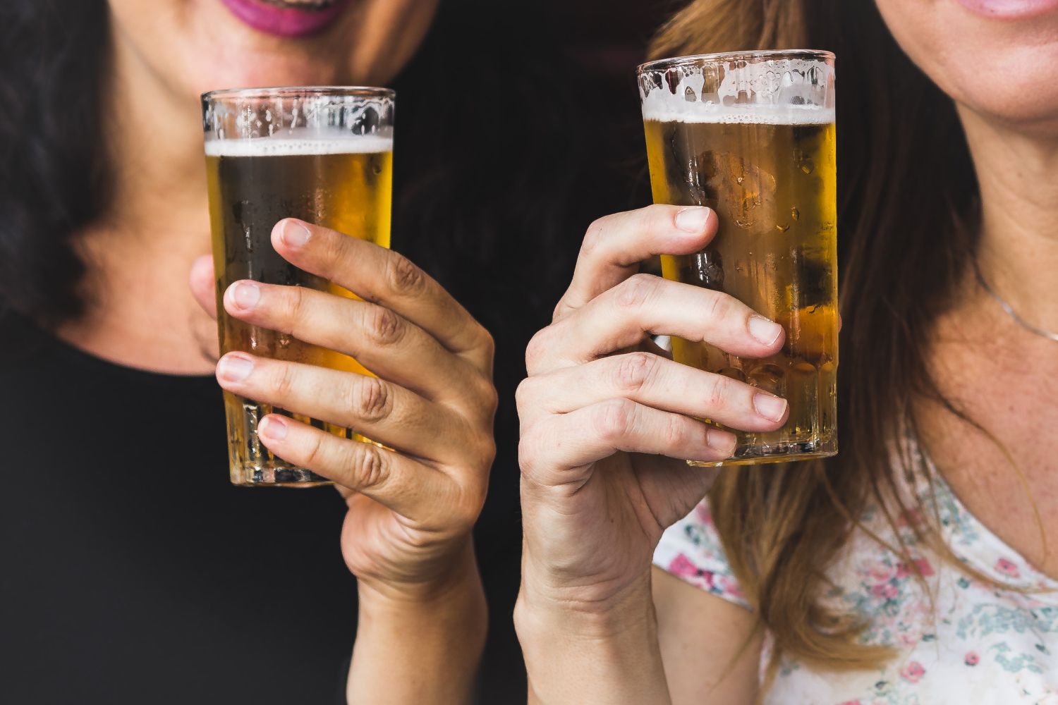 Dos personas sostienen vasos de cerveza, bebida que podría estar en peligro en el futuro / Unsplash