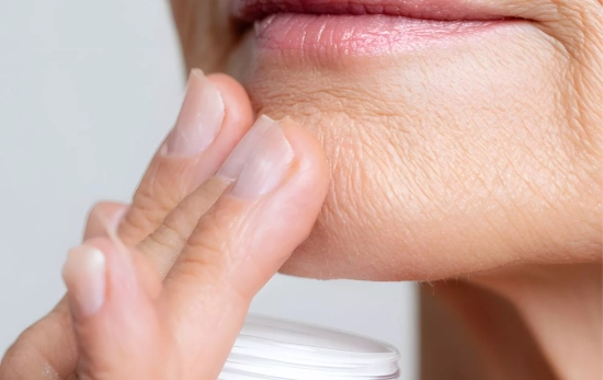 Una mujer con piel madura aplicándose una crema anti edad/ CANVA Una mujer con piel madura aplicándose una crema anti edad/ CANVA