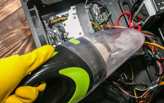 Una persona aspirando por dentro la batería del ordenador/ CANVA Una persona aspirando por dentro la batería del ordenador/ CANVA