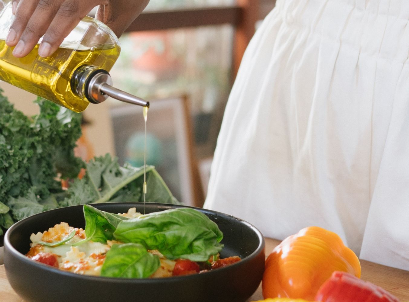 Una mujer aliña una ensalada con aceite de oliva / PEXELS