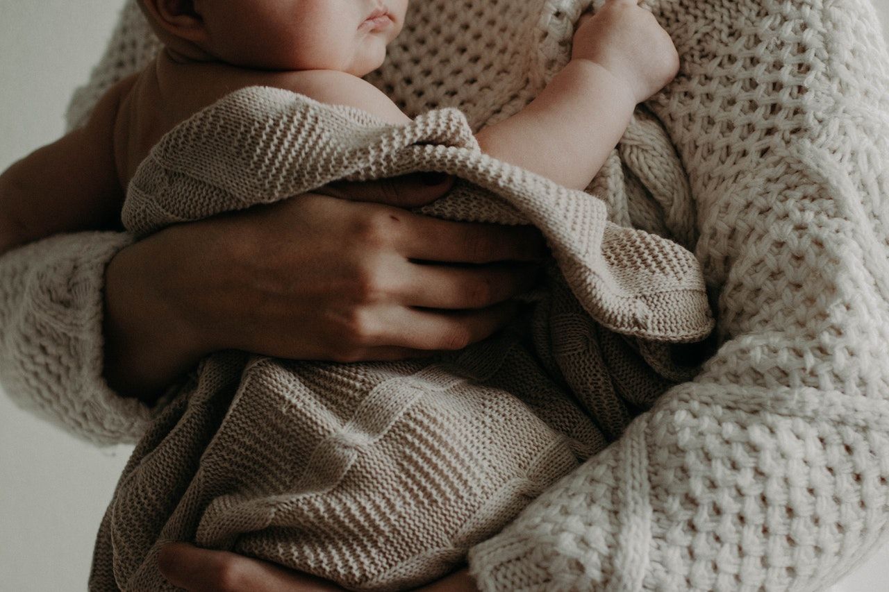 Un bebé sobre el brazo de su madre tras una gestación subrogada / PEXELS